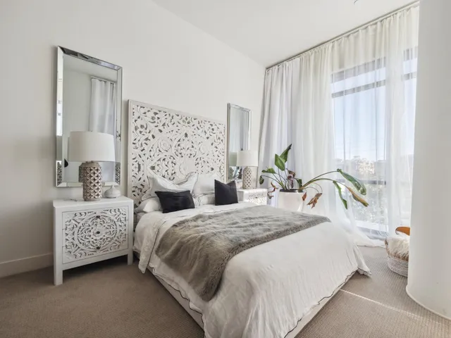 a bedroom with a bed lamp and a large window