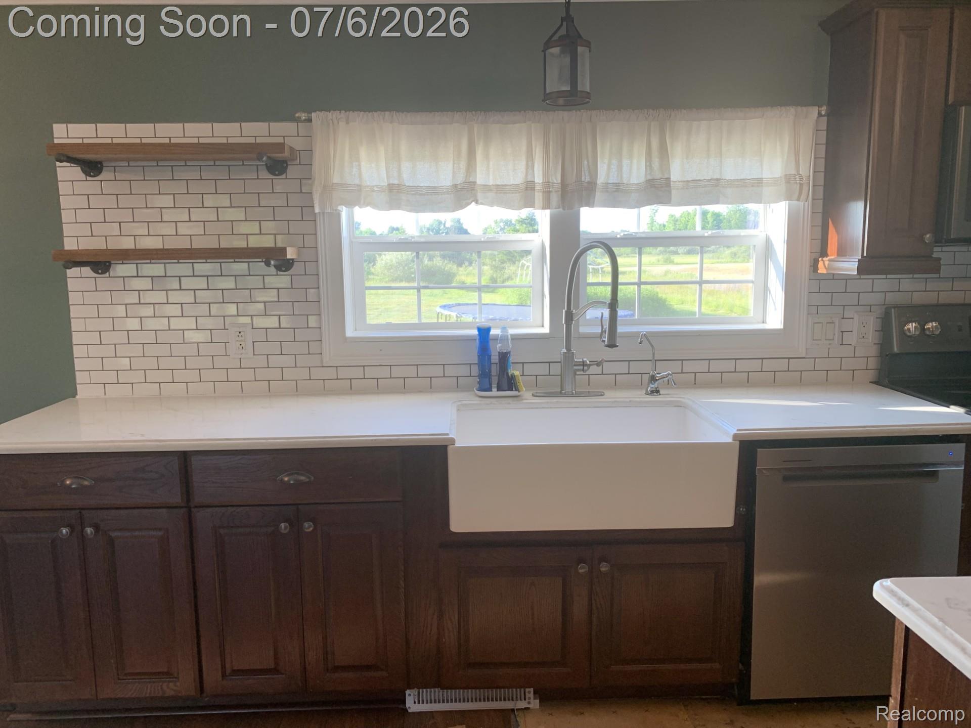 4168 Harris Road Fort Gratiot, MI 48059 - Photo 18 of 30 Kitchen featuring a white farmhouse sink, stainless steel faucet, subway tile backsplash, white countertops, and dark wood cabinetry