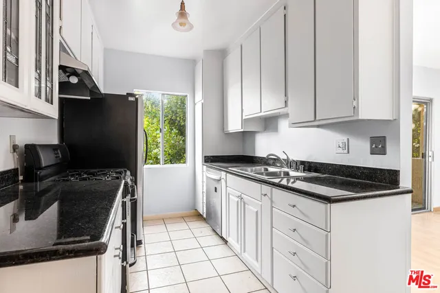a kitchen with granite countertop a stove sink and refrigerator