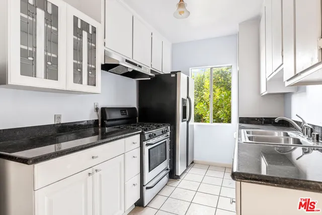 a kitchen with granite countertop a sink stainless steel appliances a counter top space cabinets and a window