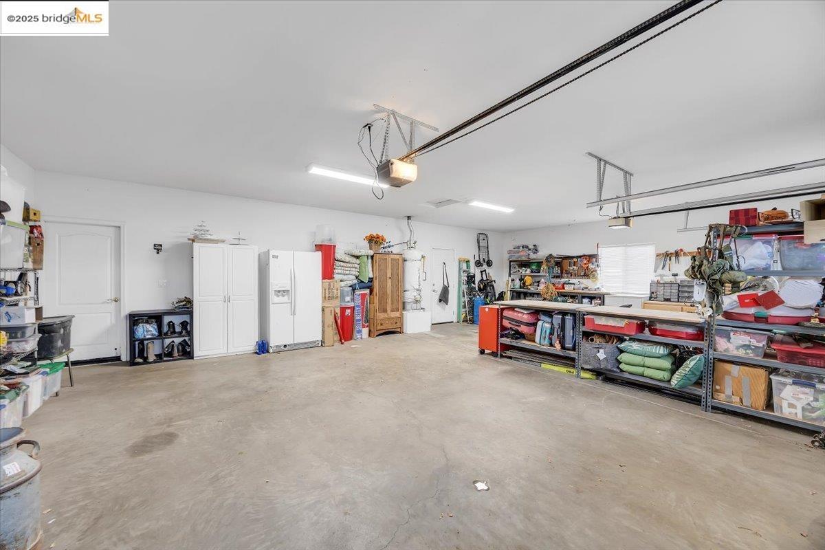 10200 Bell Mooney Road Jamestown, CA 95327 - Photo 47 of 60 Garage featuring white fridge with ice dispenser, a workshop area, and a garage door opener