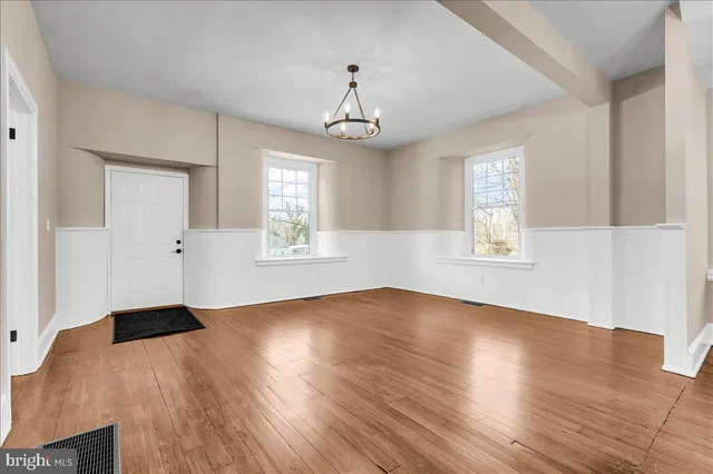 an empty room with wooden floor windows and ceiling fan