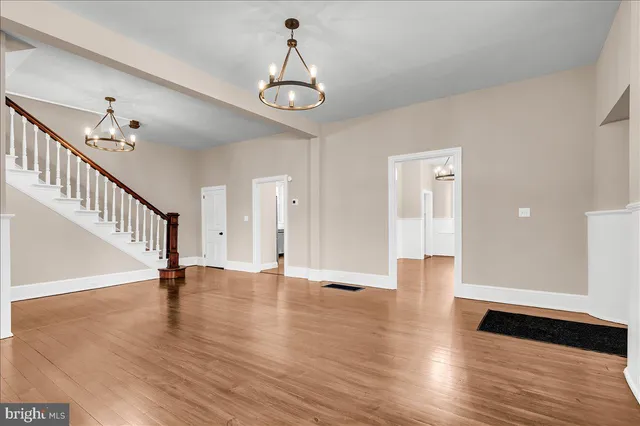 a view of an empty room with wooden floor and stairs
