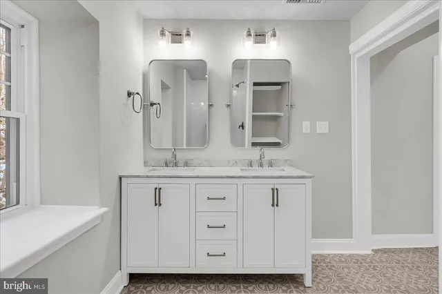 a bathroom with double vanity and a mirror