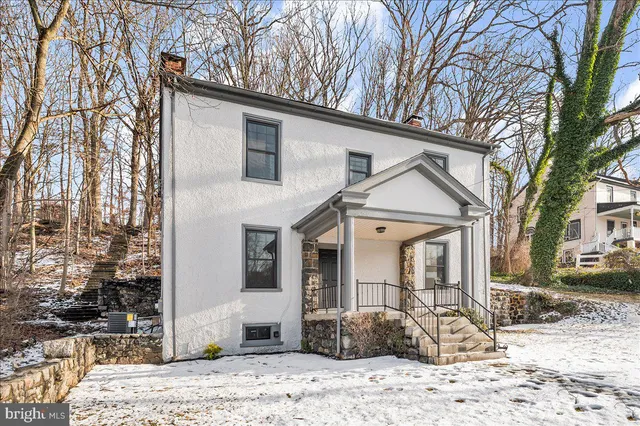 a view of a white house with a large tree