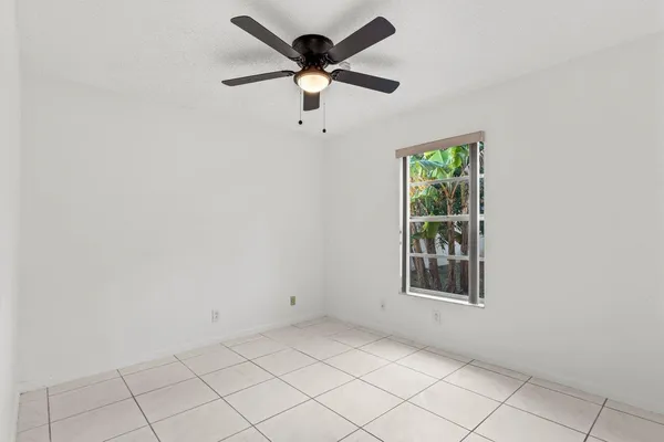 an empty room with windows and ceiling fan