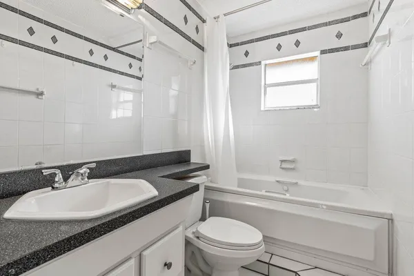 a bathroom with a granite countertop sink toilet a mirror and shower