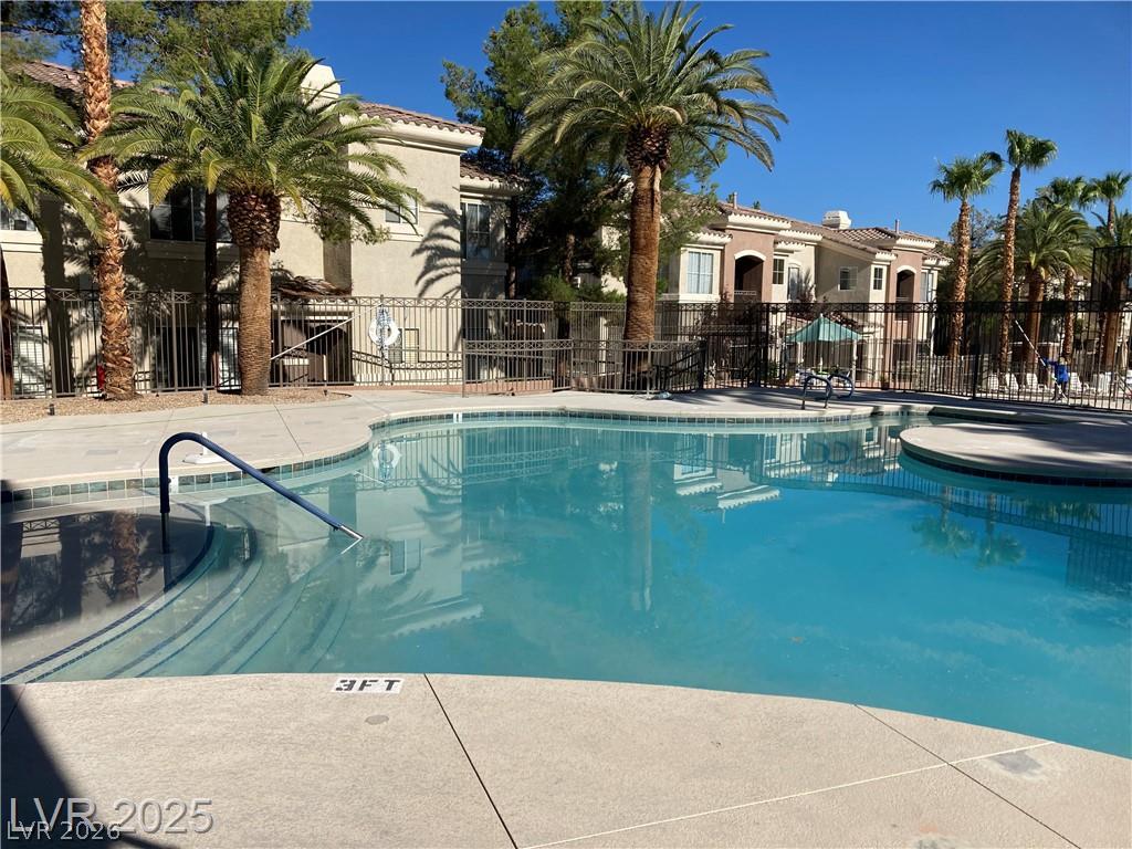 9050 West Warm Springs Road, Unit 1027 Las Vegas, NV 89148 - Photo 38 of 44 A sparkling pool offers refreshing dips against a backdrop of architectural elegance and tropical palms.