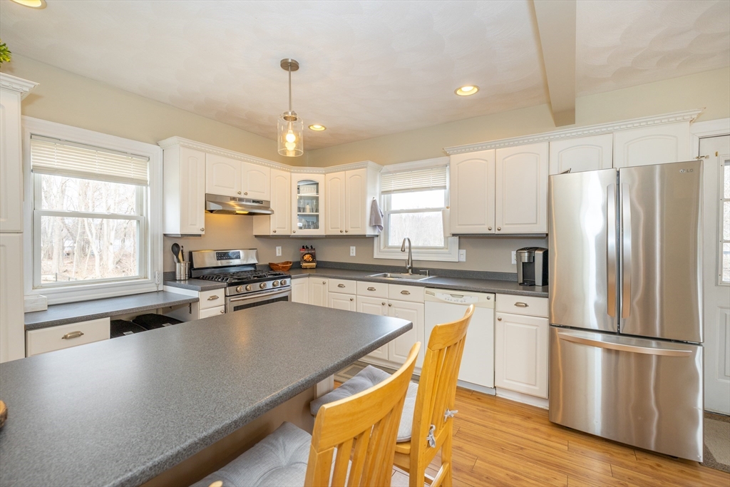 12 Post Road North Billerica, MA 01862 - Photo 6 of 38 a kitchen with stainless steel appliances a refrigerator a stove a sink dishwasher a stove and white countertops with wooden floor