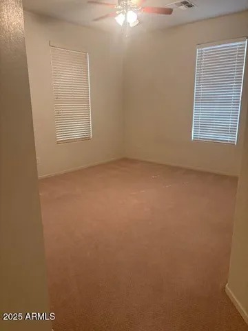 a view of an empty room with chandelier fan