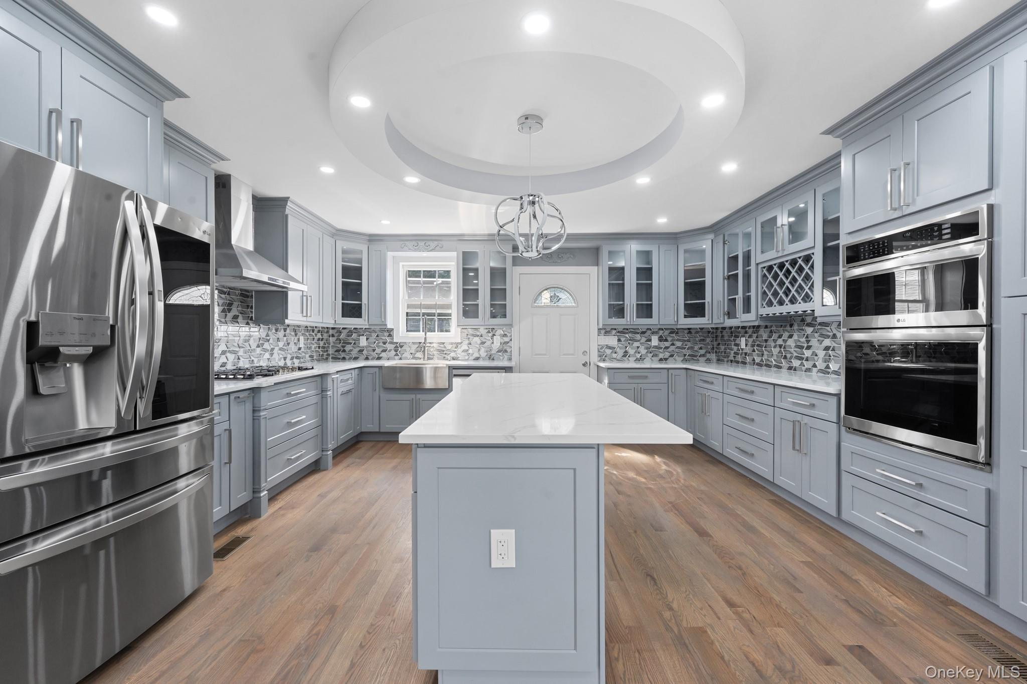 227-26 112th Road Queens, NY 11429 - Photo 1 of 1 Kitchen featuring gray cabinets, stainless steel appliances, a raised ceiling, recessed lighting, and a kitchen island
