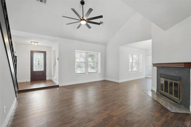 an empty room with wooden floor fireplace and windows