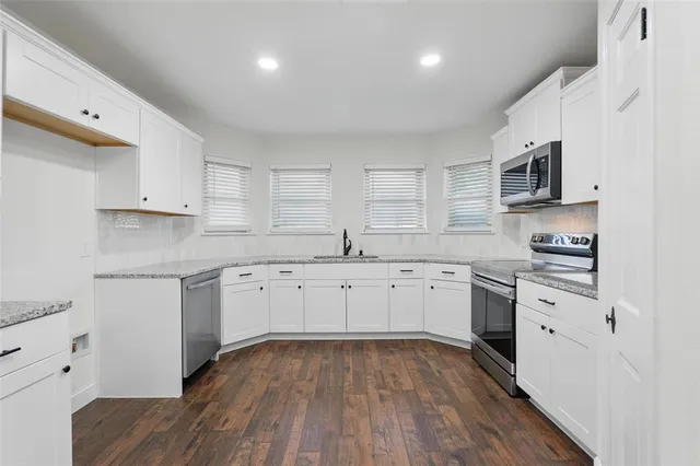 a kitchen with granite countertop white cabinets and white appliances