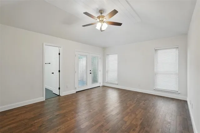an empty room with wooden floor and ceiling fan