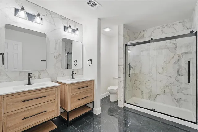 a bathroom with a double vanity sink toilet mirror and shower
