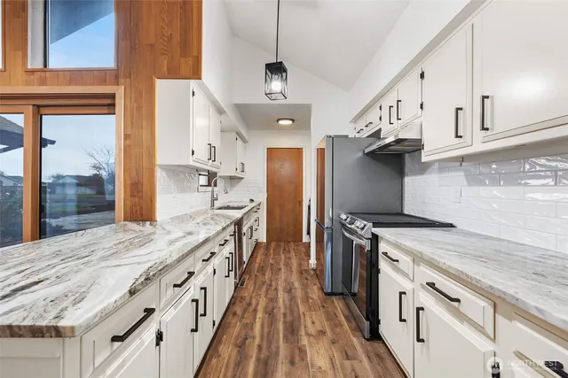 a kitchen with granite countertop a sink appliances and cabinets