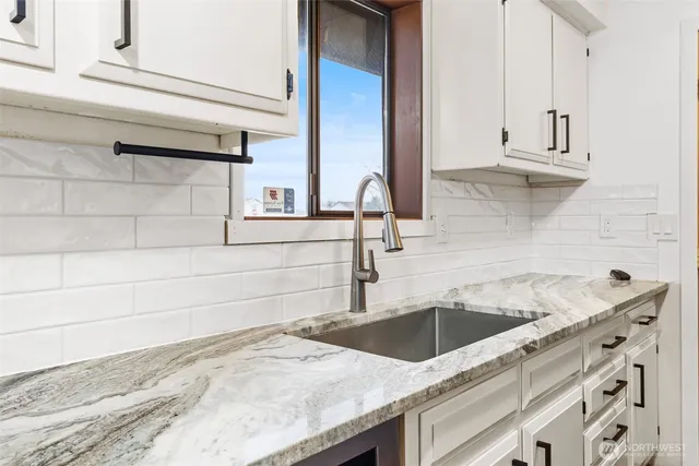 a kitchen with granite countertop white cabinets and sink