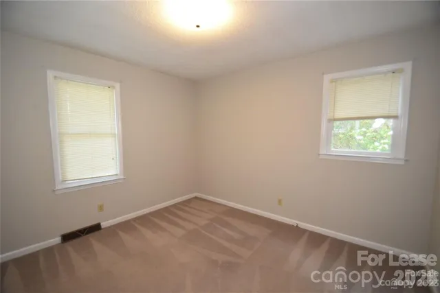 a view of a hallway with wooden floor and windows