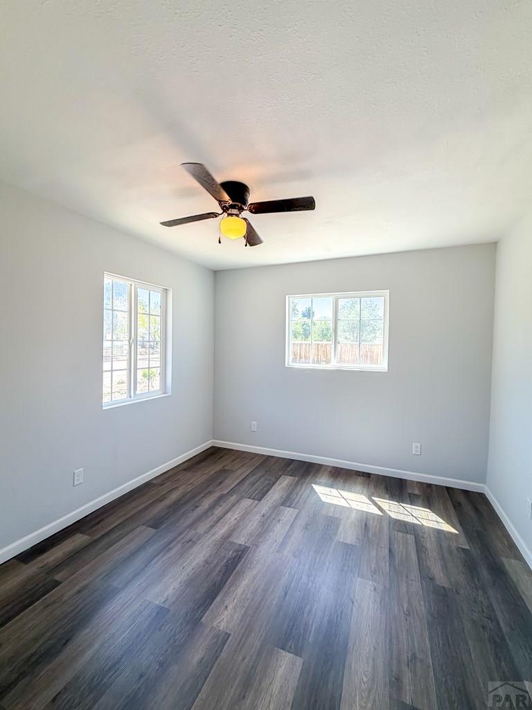 809 West 4th Street La Junta, CO 81050 - Photo 3 of 15 an empty room with wooden floor a ceiling fan and windows