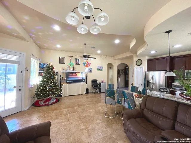 a living room with furniture kitchen view and a chandelier