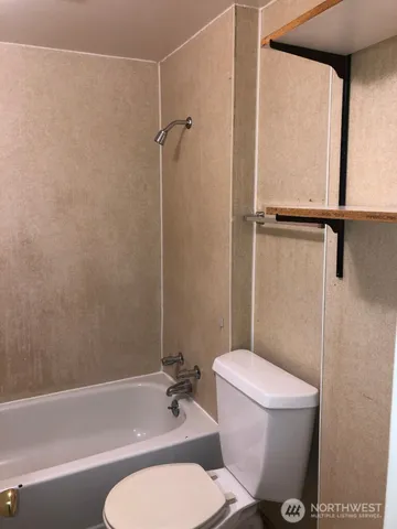 a white toilet sitting next to a bath tub