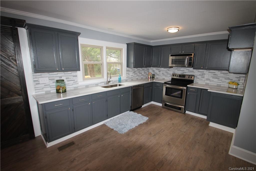 4645 Poplar Tent Road Concord, NC 28027 - Photo 8 of 25 a kitchen with stainless steel appliances granite countertop a sink stove refrigerator and cabinets