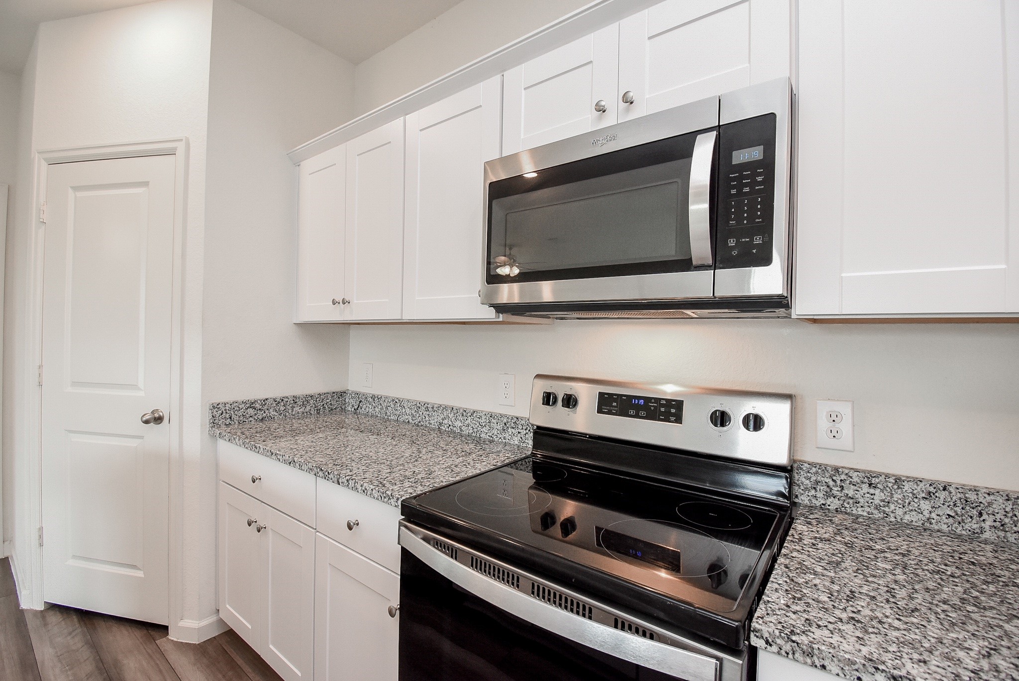 13542 Kinsman Road Houston, TX 77049 - Photo 11 of 43 a kitchen with wooden floor white cabinets and stainless steel appliances