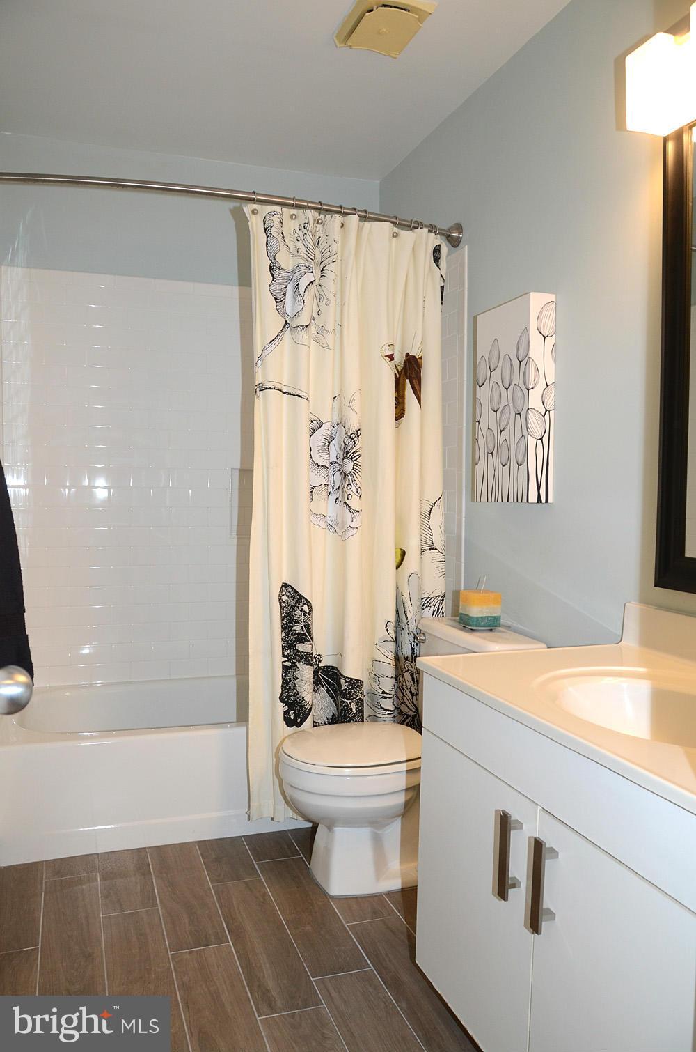 11030 Solaridge Drive Reston, VA 20191 - Photo 26 of 30 a bathroom with a granite countertop sink a toilet a mirror and a shower
