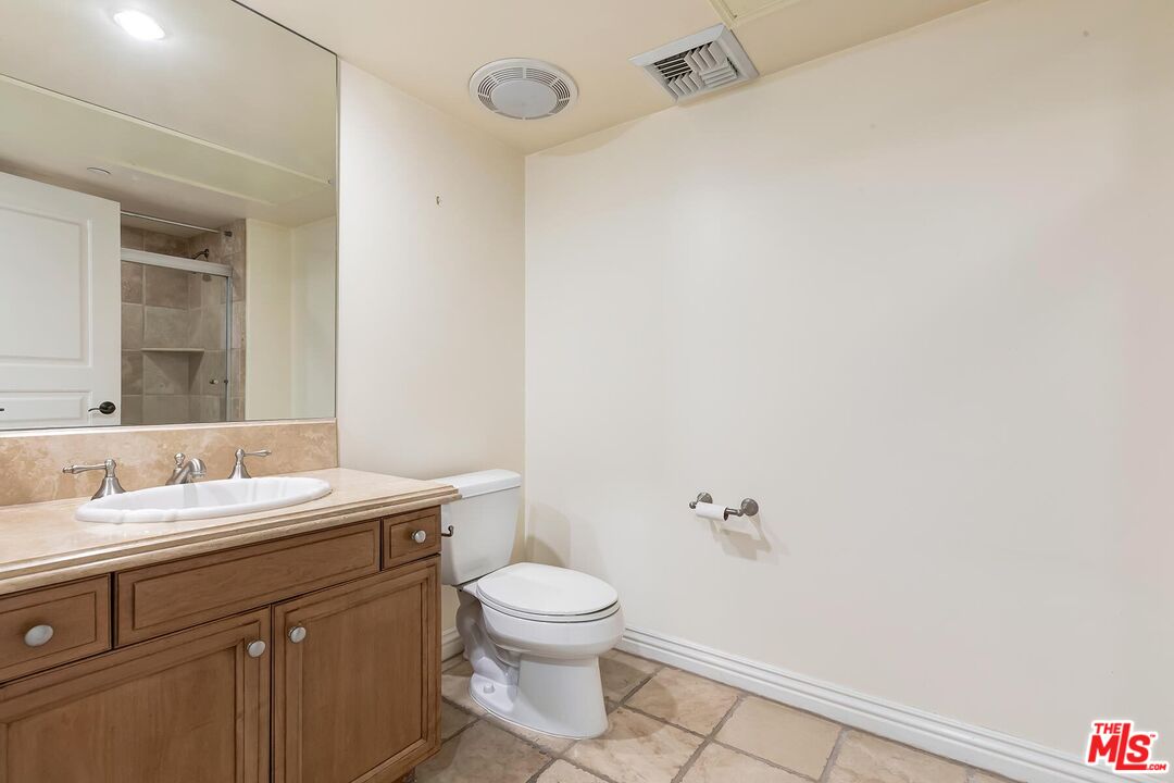 10795 Wilshire Boulevard, Unit 403 Los Angeles, CA 90024 - Photo 13 of 27 a bathroom with a granite countertop sink a toilet and a mirror