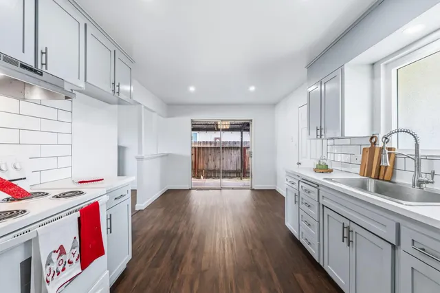 a view of a big room with wooden floor a ceiling fan and windows