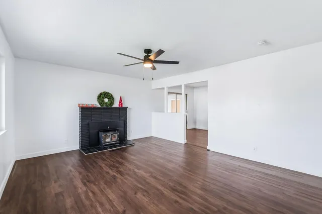 an empty room with windows fireplace and wooden floor