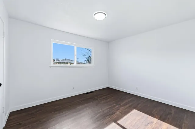 a view of an empty room with wooden floor and closet