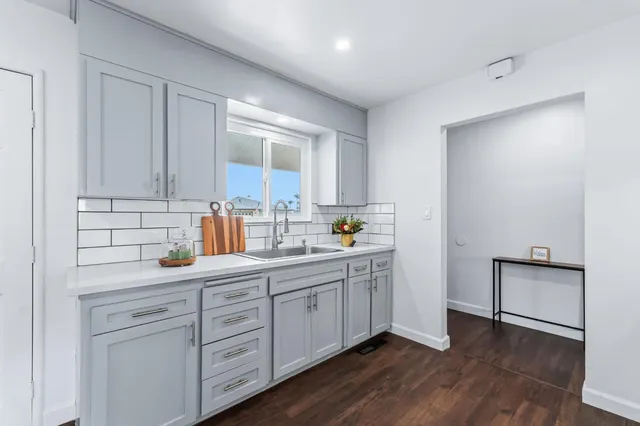 a kitchen with white cabinets and sink