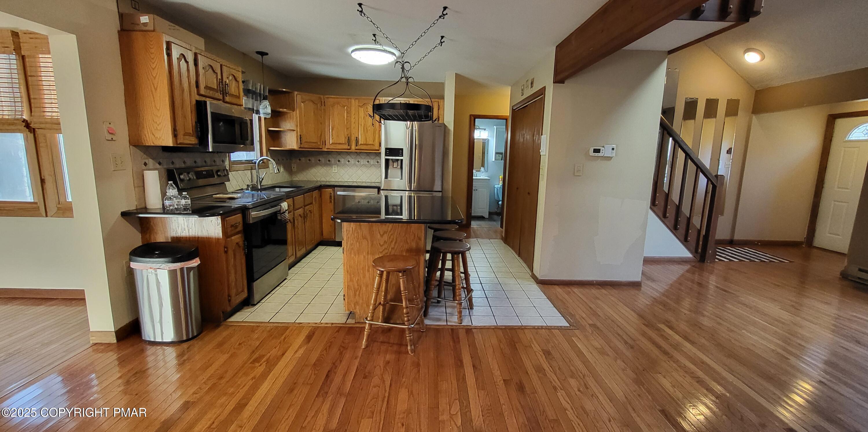 228 Edinburgh Road Bushkill, PA 18324 - Photo 10 of 77 a kitchen with wooden floors wooden cabinets stainless steel appliances a sink and a center island