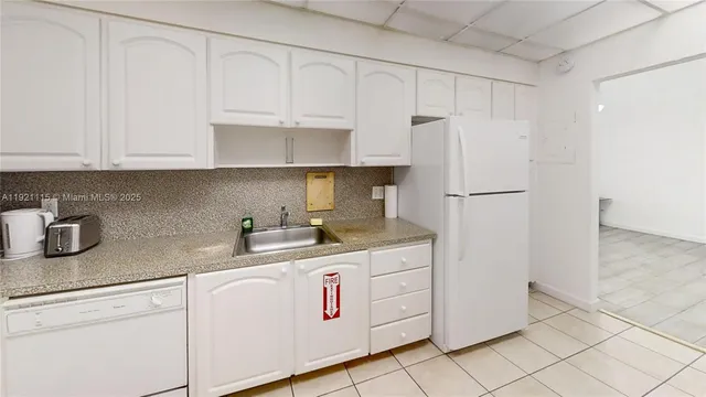 a kitchen with granite countertop white cabinets and white appliances