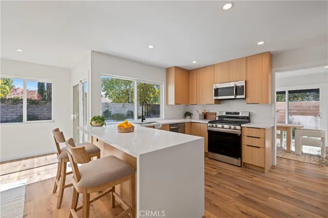 a kitchen with a stove a sink a refrigerator a dining table and chairs