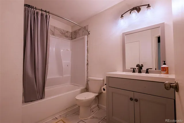 a bathroom with a sink a toilet a mirror and shower