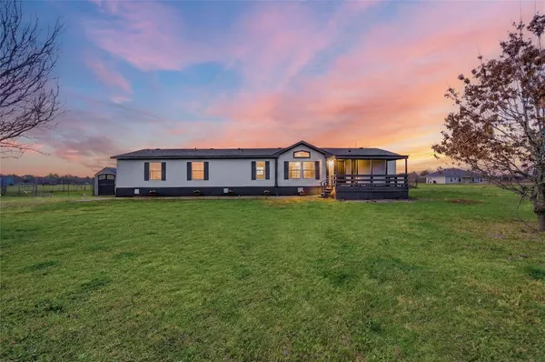 a view of a house with a big yard and large trees