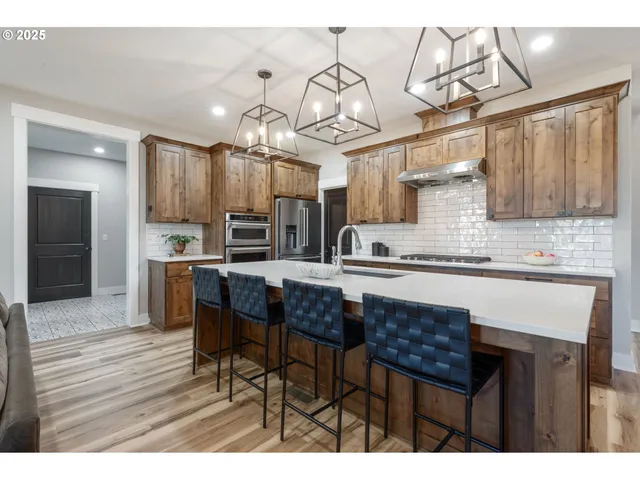 a kitchen with stainless steel appliances kitchen island granite countertop a table chairs in it and wooden floors