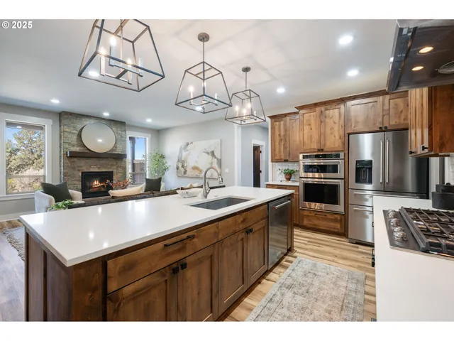 a kitchen with stainless steel appliances a sink a stove a refrigerator cabinets and a window