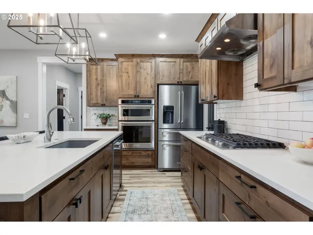 a kitchen with a sink a refrigerator and a stove top oven with wooden floor