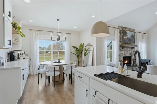 a kitchen with kitchen island granite countertop a table chairs stove a sink and dishwasher a fireplace with wooden floor