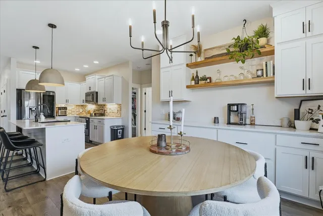a kitchen with stainless steel appliances granite countertop a sink a stove and chairs