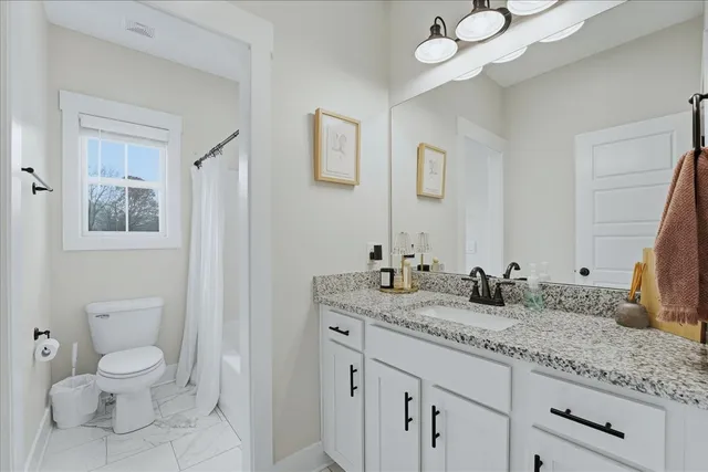 a bathroom with a granite countertop sink mirror vanity and toilet