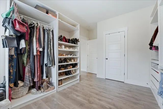 a view of walk in closet with clothes and shoes