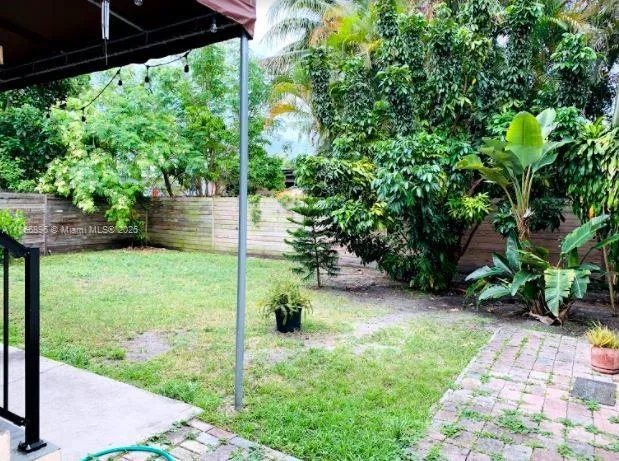 a backyard of a house with plants and large trees