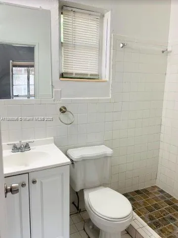 a bathroom with a toilet a sink a mirror and a window