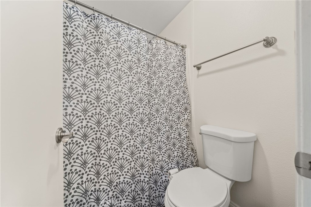 5470 Copper Canyon Road, Unit 2E Yorba Linda, CA 92887 - Photo 9 of 25 a white toilet sitting next to a shower curtain