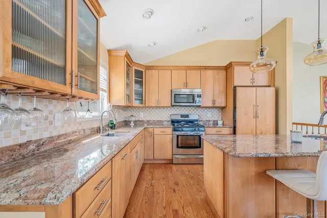 a kitchen with stainless steel appliances kitchen island granite countertop a table chairs and a refrigerator