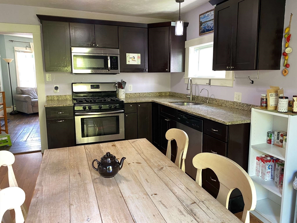 8 May Street Beverly, MA 01915 - Photo 9 of 25 a kitchen with granite countertop a stove a sink and wooden cabinets